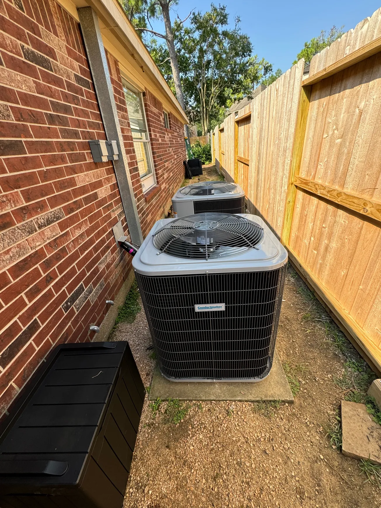 Dual residential condensers serviced beside a home